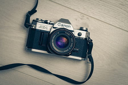 black and silver Canon MILC on brown wooden surface thumbnail
