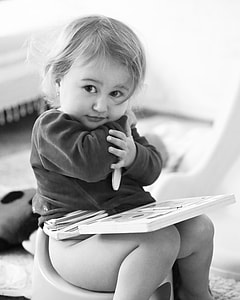 grayscale of girl sitting on potty training with boon on her lap thumbnail