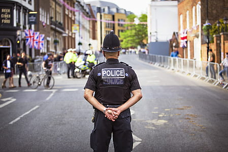 police man standing in the middle of road during daytime thumbnail