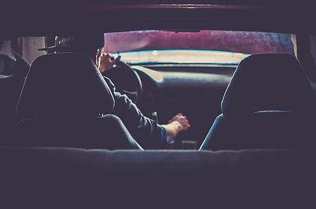 man with black fitted cap inside car and holding gear shift lever thumbnail