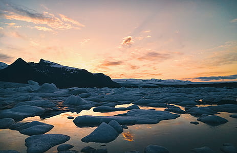 ice berg on body of water near mountain at sunset thumbnail