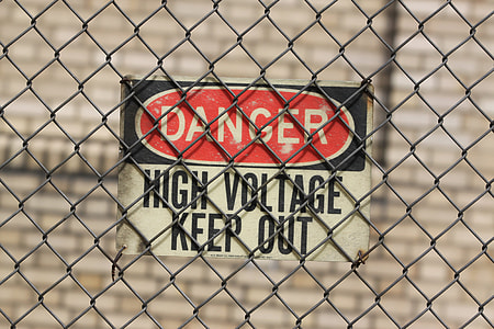 danger high voltage keep out signage on black chain-link fence thumbnail