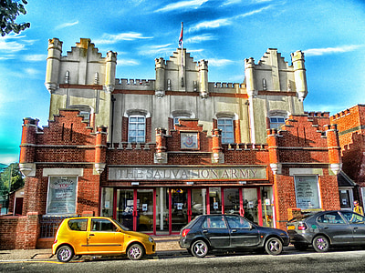 three black and yellow vehicles parked in-front of The Saliva Hon Army building painting thumbnail