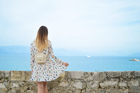 woman standing in front of sea wall near body of water thumbnail