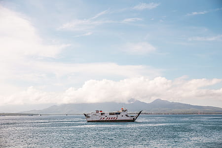 White ferry in clear blue water surrounded by mountains thumbnail