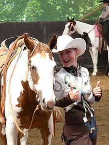 woman standing next to white and brown horse at daytime thumbnail