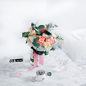 pink and yellow flowers in clear glass vase centerpiece on white table thumbnail