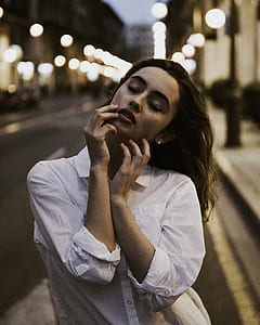 woman closing eyes holding her face selective focus photography thumbnail