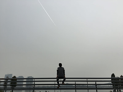 man sitting on gray bars under gray sky thumbnail