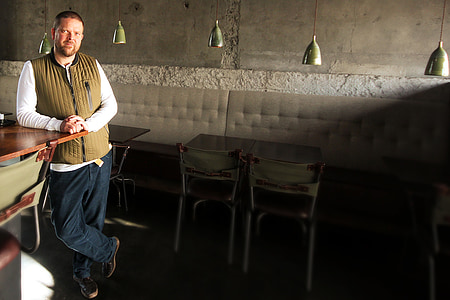 man standing beside brown wooden table thumbnail