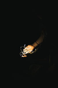 low light photography of person holding white string lights thumbnail