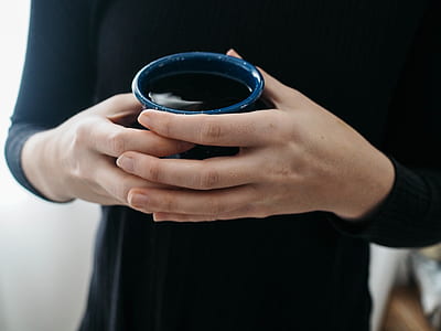 person holding blue cup near white wall thumbnail