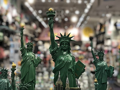 four Statue of Liberty figurines in selective focus photography thumbnail