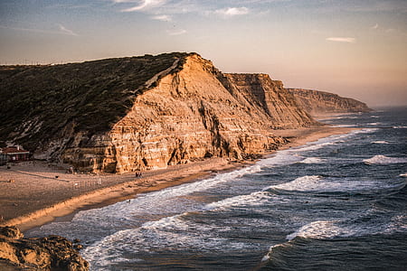 brown mountain near sea during daytime photography thumbnail