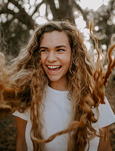 woman wearing white t-shirt smiling near tree thumbnail