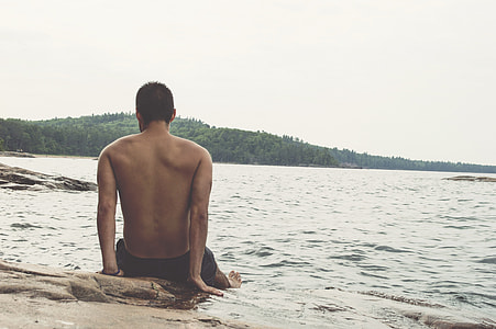 man sitting on sand near seashore during daytime thumbnail
