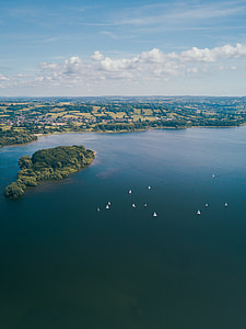 aerial photography of boats sailing near island during daytime thumbnail