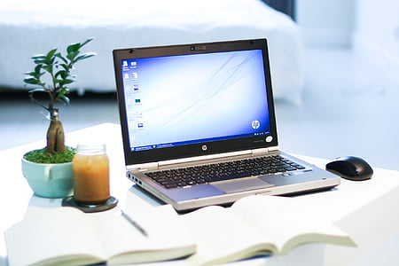 black and gray HP laptop computer on white wooden table thumbnail