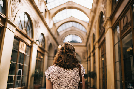 selective focus photography of woman wears white and black top standing between of concrete building thumbnail