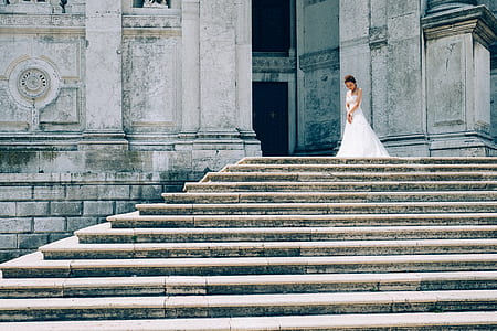 woman wearing white wedding gown standing on top of stairs thumbnail