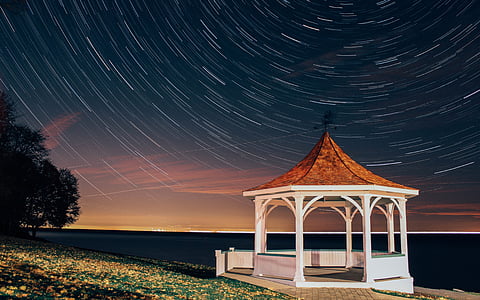 time lapse photo of wooden canopy near body of water thumbnail