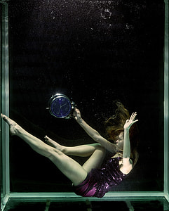 woman wearing sequinned purple top holding silver bell alarm clock thumbnail