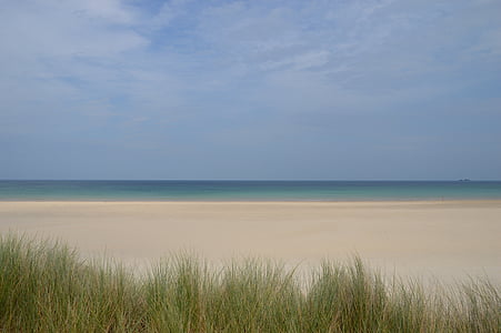 beige beach overlooking body of water under blue daytime sky thumbnail