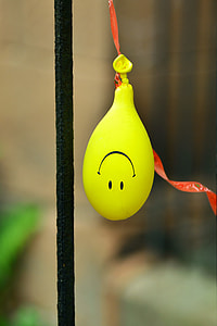 yellow balloon with smiley emoticon print hanging beside black steel rod thumbnail