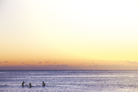 three person swimming in sea during sunset thumbnail