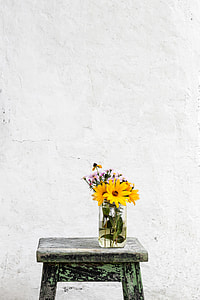 closeup photo of yellow sunflower in vase on top of brown stool thumbnail