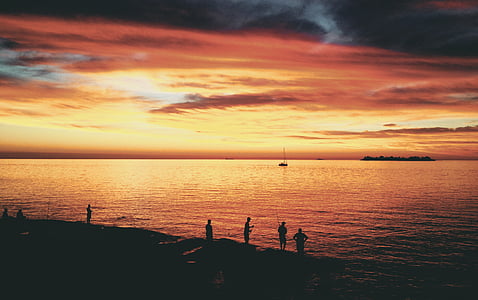 silhouette of people standing on seashore during golden hour thumbnail
