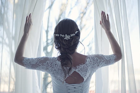 woman wearing white long-sleeved laced top holding white curtains thumbnail