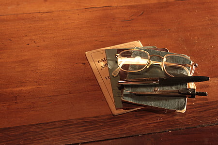 gold-colored framed eyeglasses near two click pens thumbnail