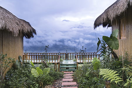 two brown wooden houses with baluster facing cloudy mountain thumbnail