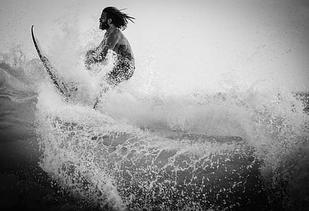 grayscale photography of man riding surfboard on sea thumbnail