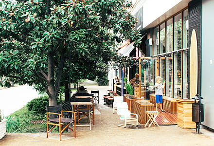Child Outside Building Near Wooden Furniture and Tree thumbnail