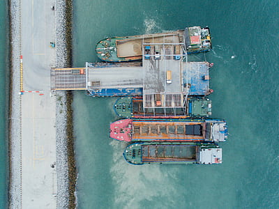bird's eye view photo of four assorted-color garbage boat on body of water thumbnail