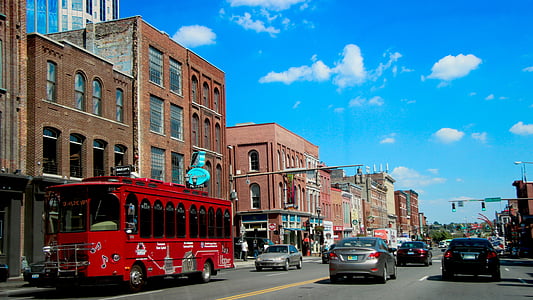 red bus along with assorted cars on road under blue and white cloudy sky at day thumbnail