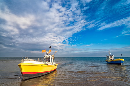 yellow and white fishing vessel on seashore thumbnail