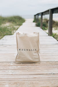 shallow focus photography of Magnolia bag on wooden dock thumbnail