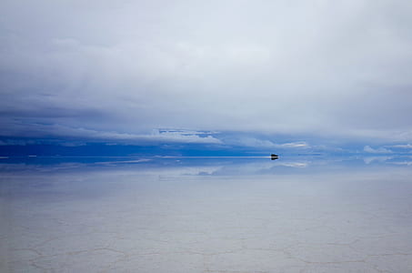 black boat on body of water under cloudy skies thumbnail