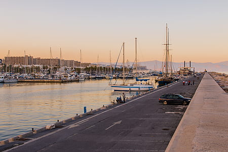 Black Car Near Body of Water With Boats on Harbor Dock thumbnail
