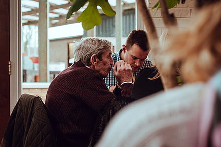 man sitting beside man near glass panel window thumbnail