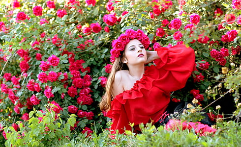 woman sitting on grass field near red petaled flowers thumbnail