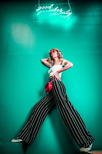 woman wearing white crop top leaning on teal wall thumbnail