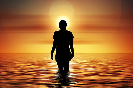 silhouette woman in calm body of water during sunset thumbnail