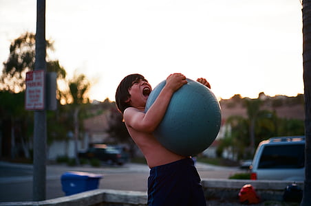 boy carrying blue stability ball thumbnail