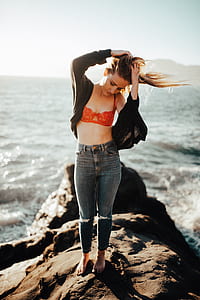 woman standing on rock near body of water thumbnail