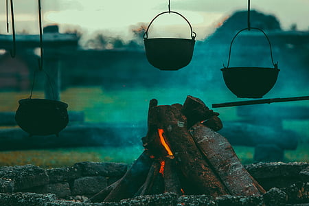 three cooking pots hanging over wood fire on pit thumbnail