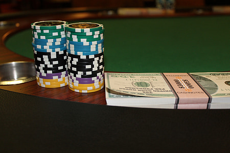 stack of poker chips beside bundle of banknotes on table thumbnail